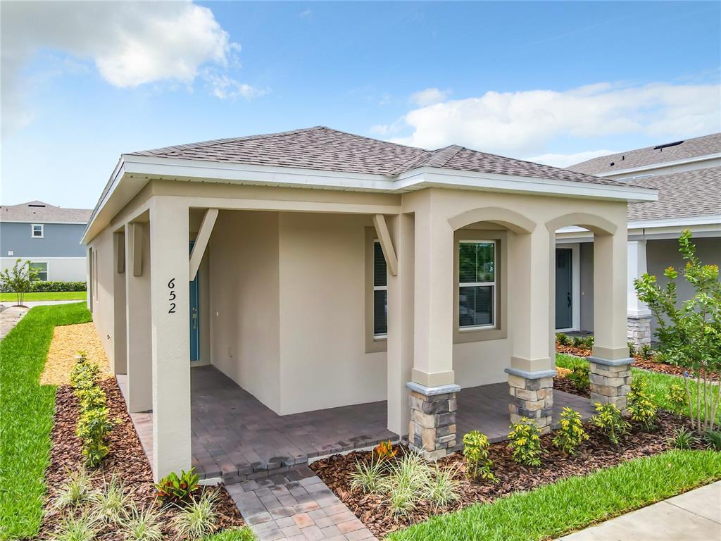A single-story house with a covered front porch, stone-based columns, and a paved walkway — 652 KIMBER LANE, DEBARY, FL