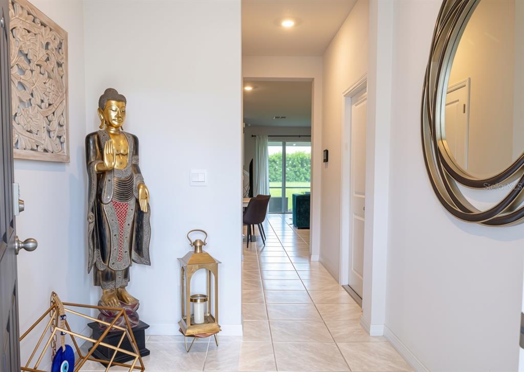 An entryway features a tall Buddha statue, a gold lantern, and a large oval mirror — 17632 CRESCENT MOON LOOP, BRADENTON, FL