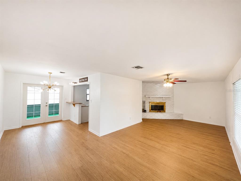A living room with light wood floors, a white brick fireplace, and a dining area — 44 S CORTEZ AVENUE, WINTER SPRINGS, FL