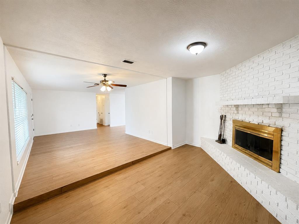 A living room features a sunken floor area, light wood-look flooring, and a white brick fireplace — 44 S CORTEZ AVENUE, WINTER SPRINGS, FL
