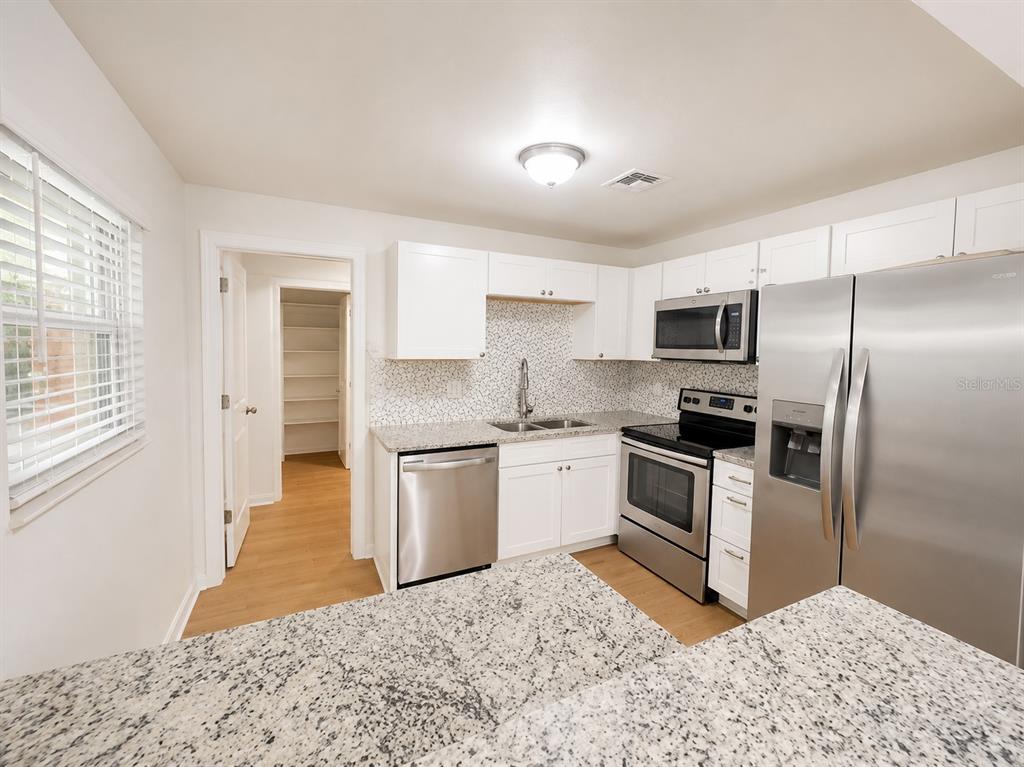 A kitchen features white cabinets, granite countertops, stainless steel appliances, and a tiled backsplash — 44 S CORTEZ AVENUE, WINTER SPRINGS, FL