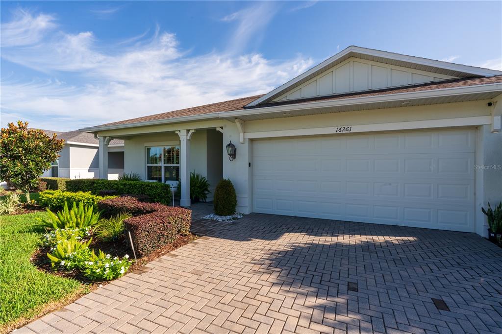 A single-story house features a white garage door, a paved driveway, and manicured landscaping — 16261 YELLOWEYED DRIVE, CLERMONT, FL
