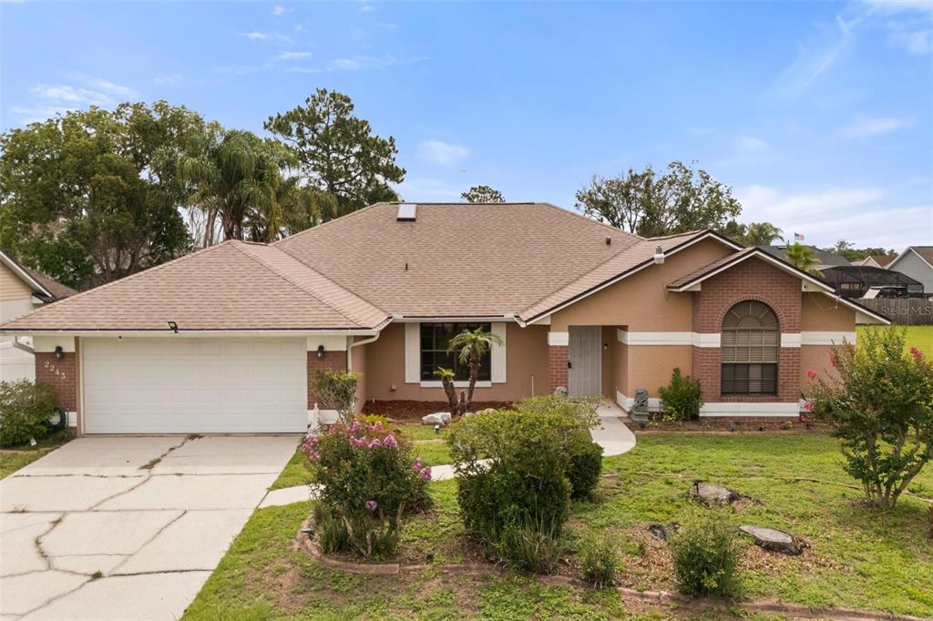 A single-story suburban house with a concrete driveway and a large tree in the yard — 2243 BANCROFT BOULEVARD, ORLANDO, FL