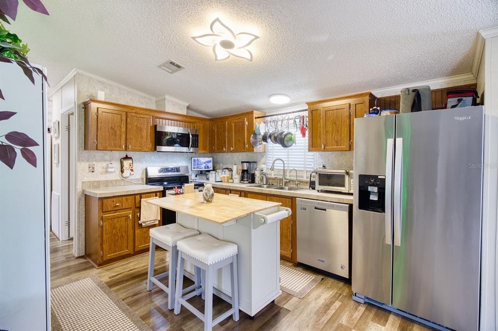A kitchen with wood cabinets, stainless steel appliances, a central island, and wood-look flooring — 2201 S RIDGEWOOD AVENUE UNIT 28, EDGEWATER, FL