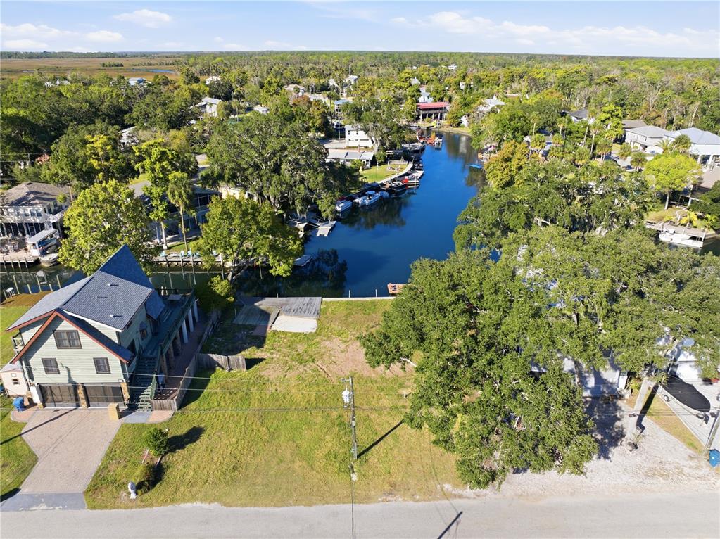 An aerial view shows a vacant waterfront lot situated between two houses and a canal — 00 CIRCLE DRIVE, WEEKI WACHEE, FL