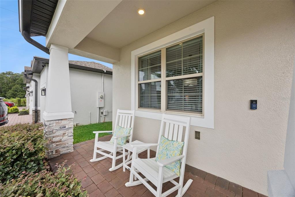 A covered front porch features two white rocking chairs on a brick paver floor — 162 BLUE FLAX POINT, LONGWOOD, FL