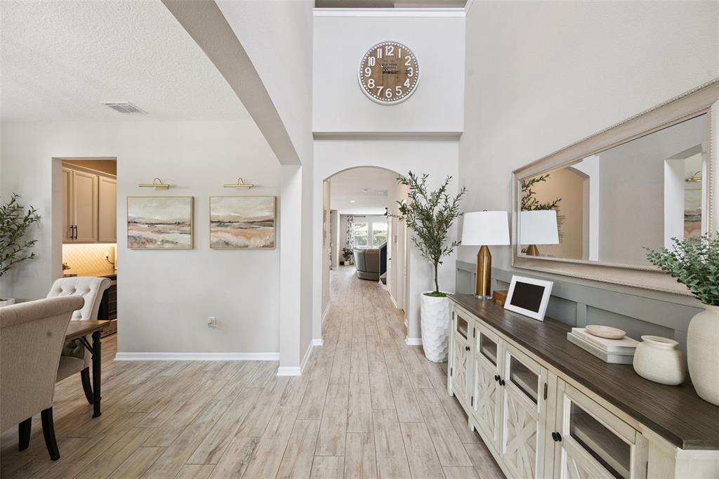 A bright entryway features wood-look tile flooring, a console table, and a large wall clock — 162 BLUE FLAX POINT, LONGWOOD, FL