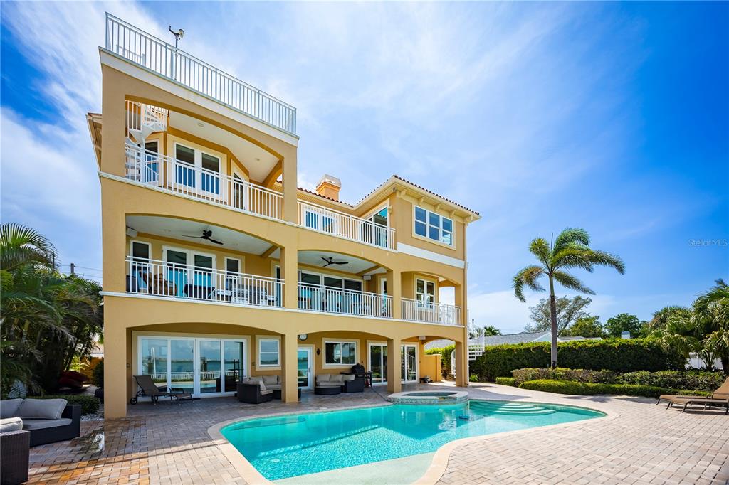A three-story yellow house with balconies, a swimming pool, and a paved patio area — 306 HARBOR DRIVE, INDIAN ROCKS BEACH, FL