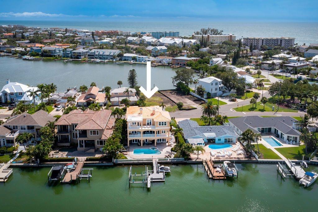 An aerial view shows a waterfront house with a pool next to a vacant lot — 306 HARBOR DRIVE, INDIAN ROCKS BEACH, FL