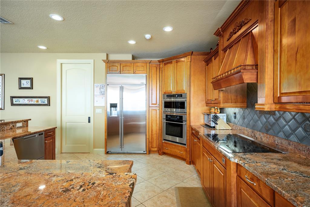 A kitchen features wood cabinets, granite countertops, stainless steel appliances, and a tiled backsplash — 306 HARBOR DRIVE, INDIAN ROCKS BEACH, FL