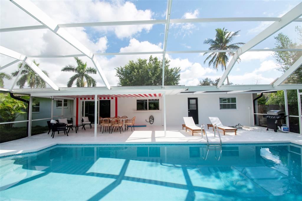 A swimming pool with a screened-in patio featuring outdoor furniture and a grill — 59 WICKLIFFE DRIVE, NAPLES, FL