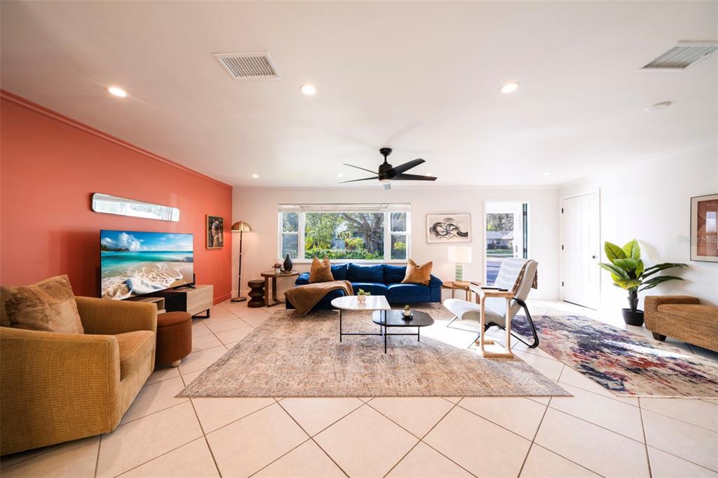 A living room features a coral accent wall, blue sofa, tile flooring, and a ceiling fan — 59 WICKLIFFE DRIVE, NAPLES, FL
