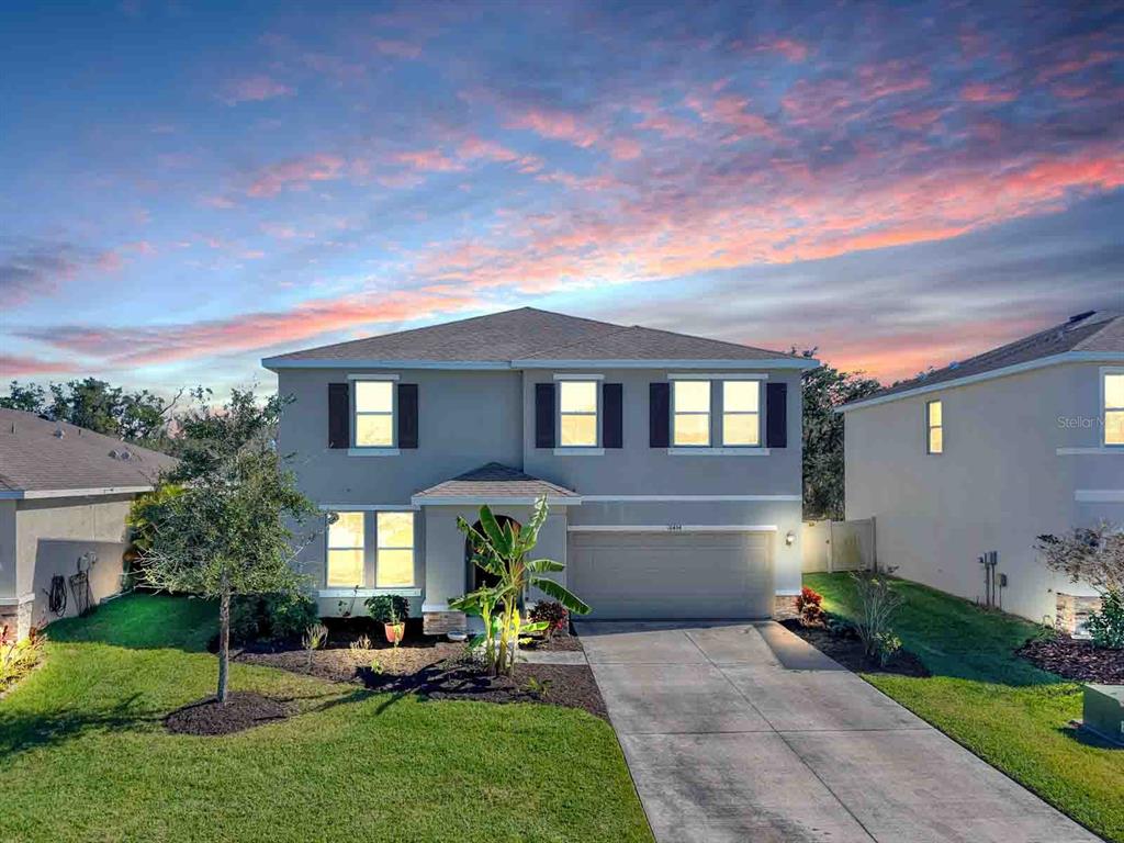 A two-story suburban house with a gray exterior, brown roof, and a concrete driveway — 16454 WOODSIDE GLEN, PARRISH, FL