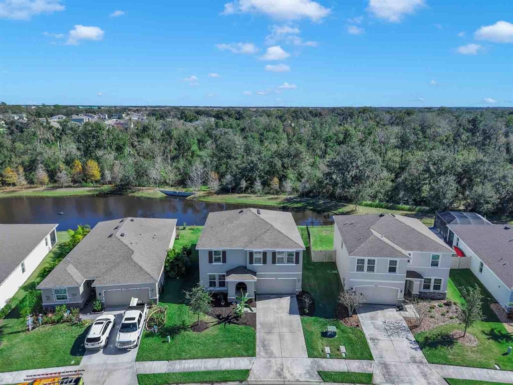 An aerial view shows three suburban houses with driveways facing a pond and wooded area — 16454 WOODSIDE GLEN, PARRISH, FL