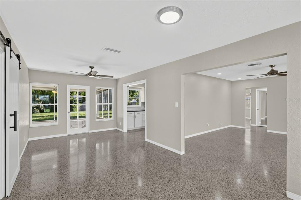 An open-concept living area features polished speckled floors, neutral walls, and two ceiling fans — 5825 21ST AVENUE S, GULFPORT, FL