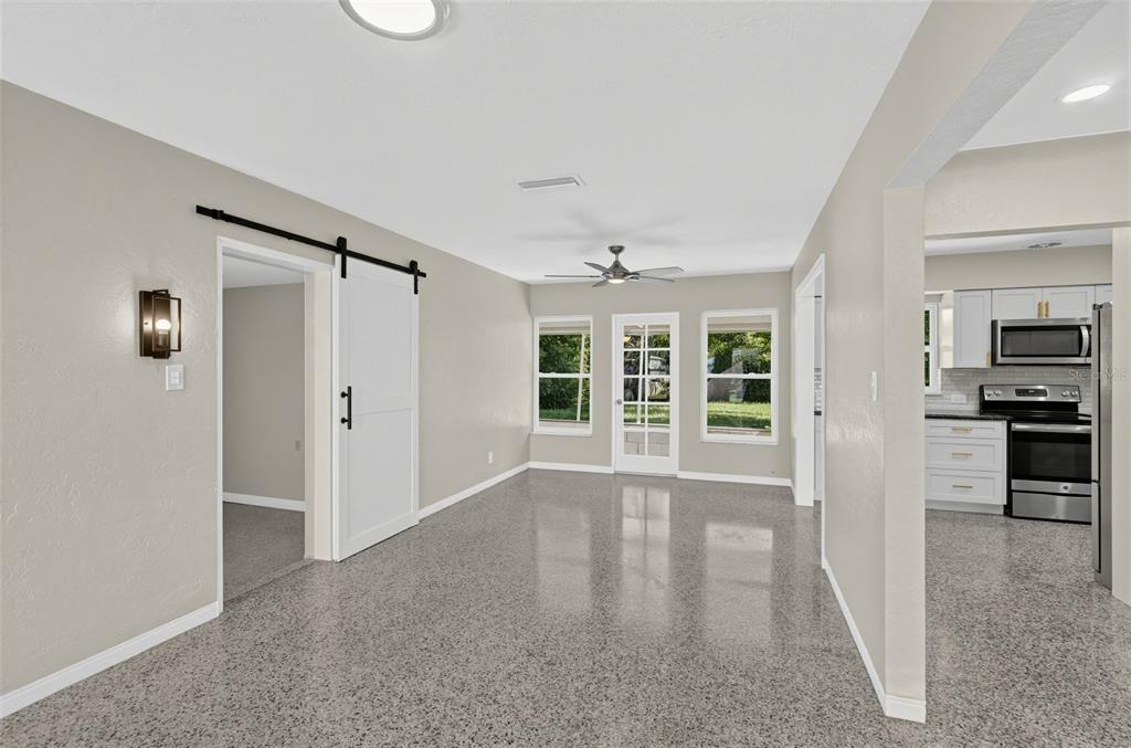 A dining area with speckled flooring, a sliding barn door, and a view into the kitchen — 5825 21ST AVENUE S, GULFPORT, FL