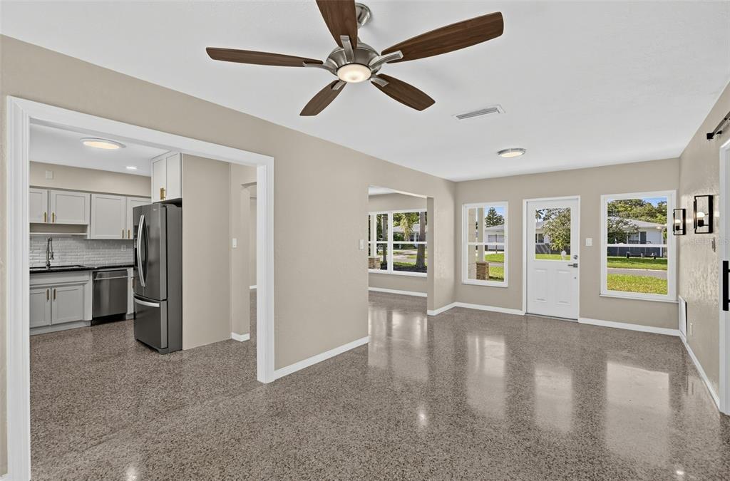 An open-concept living area with polished concrete floors, a ceiling fan, and an adjacent kitchen — 5825 21ST AVENUE S, GULFPORT, FL
