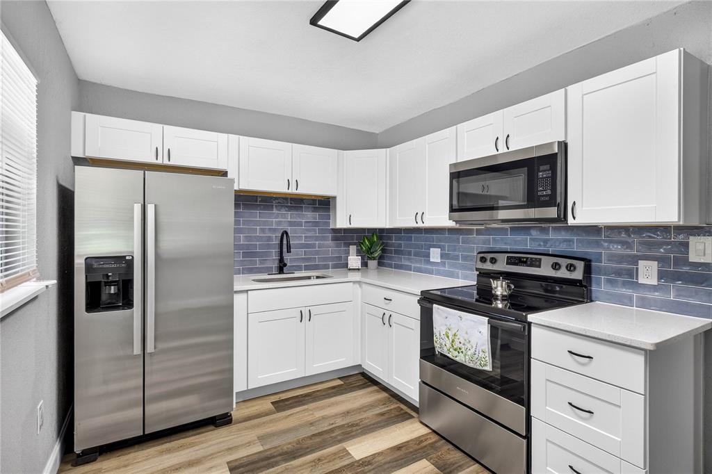 A kitchen features white cabinets, stainless steel appliances, and a blue subway tile backsplash — 1803 E OHIO STREET, PLANT CITY, FL