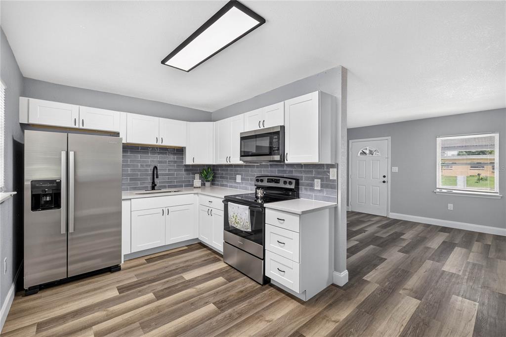 A kitchen with white cabinets, stainless steel appliances, and gray subway tile backsplash — 1803 E OHIO STREET, PLANT CITY, FL