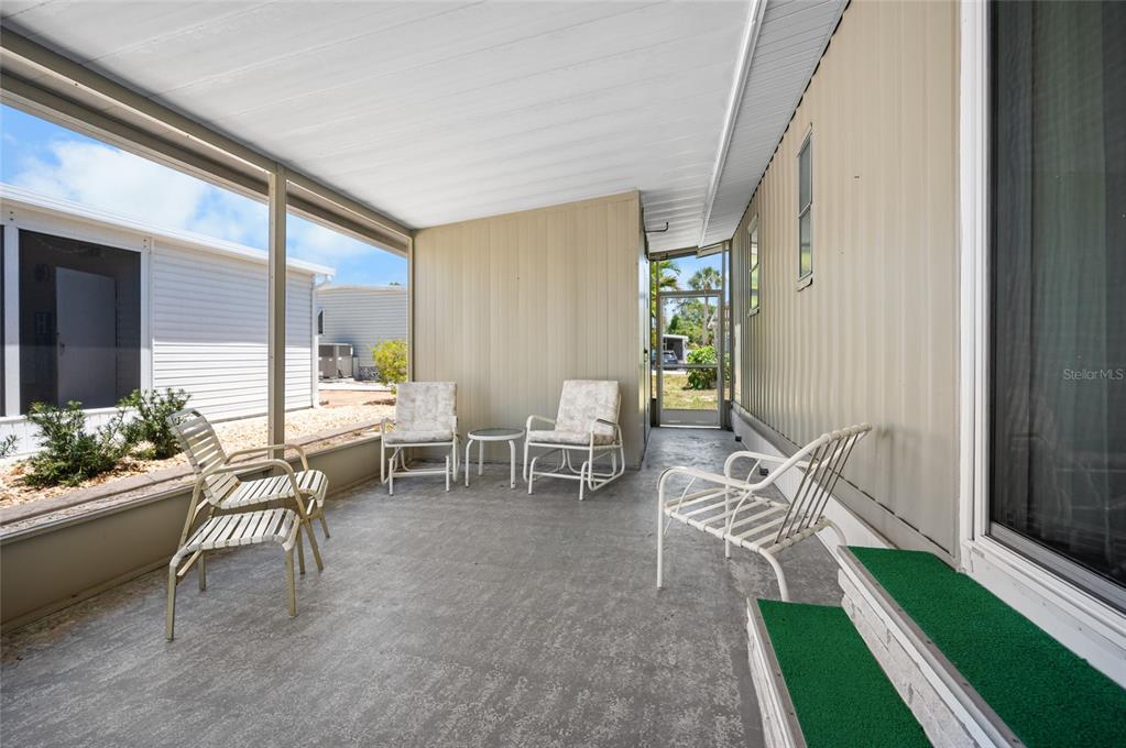 A screened-in porch features a concrete floor, metal siding, and several outdoor chairs — 5751 HYACINTH ROAD, VENICE, FL