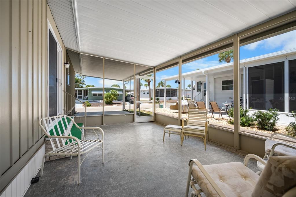 A screened-in concrete patio features outdoor furniture and views of neighboring mobile homes — 5751 HYACINTH ROAD, VENICE, FL