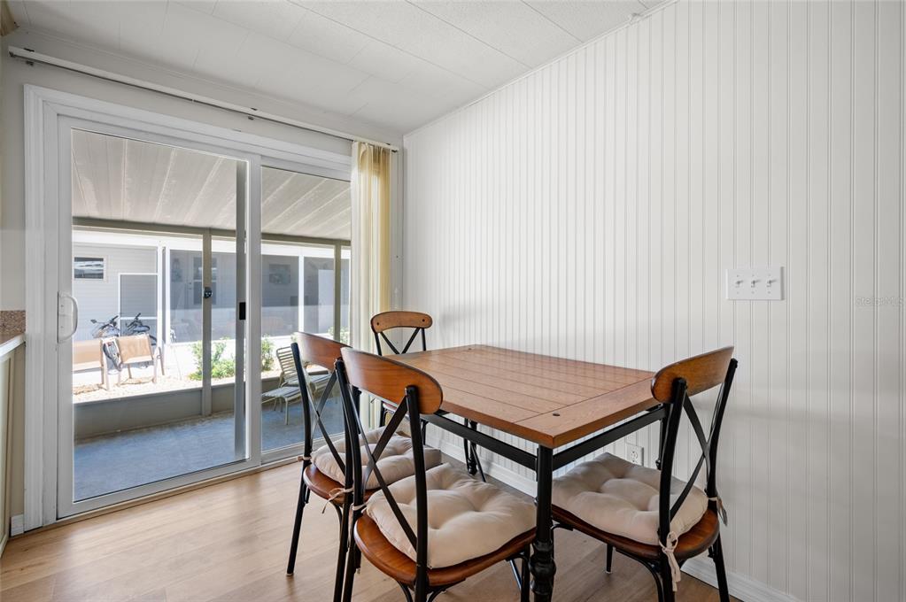 A dining area features a wooden table with four chairs, beadboard walls, and sliding glass doors — 5751 HYACINTH ROAD, VENICE, FL