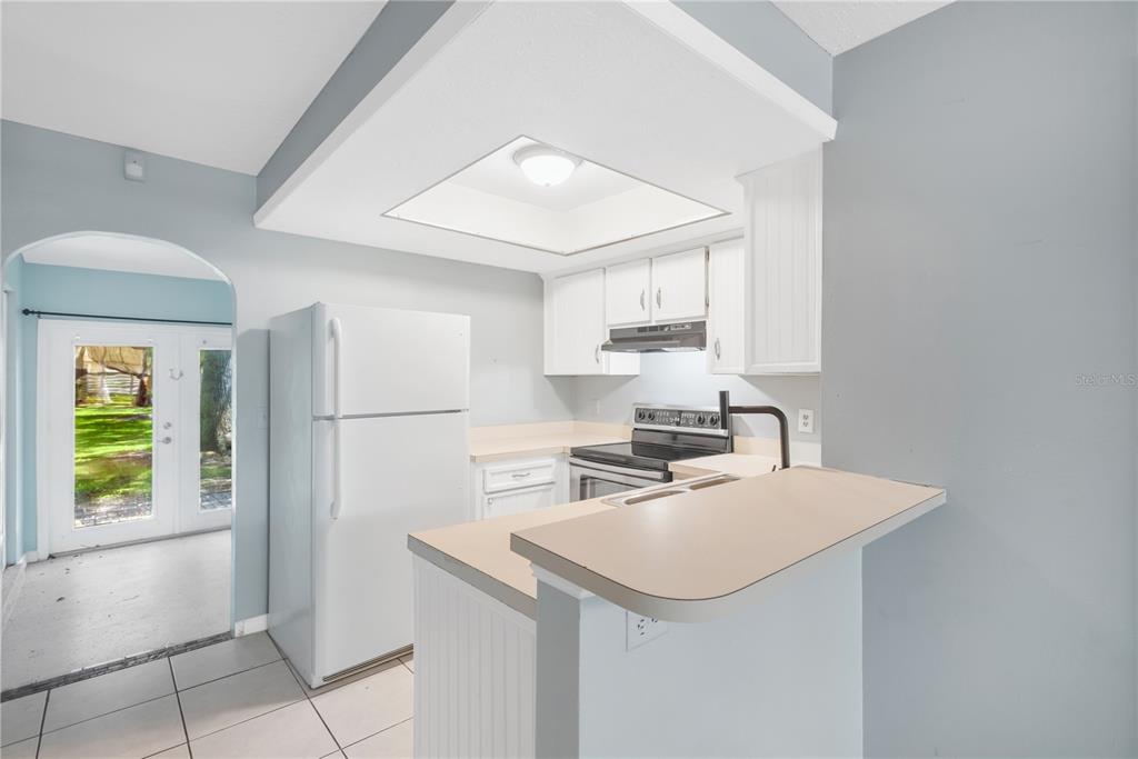 A kitchen with white cabinets, a white refrigerator, and a breakfast bar with beige countertops — 609 SAINT HENRY DRIVE, BRANDON, FL