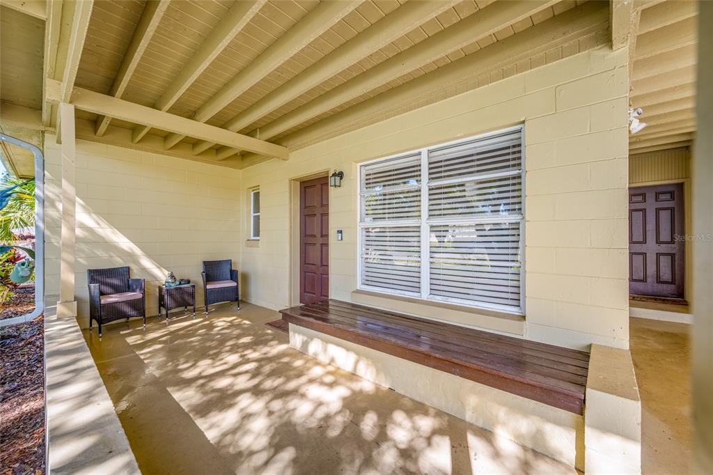 A covered porch features a wooden bench, two chairs, and two brown doors — 6410 WALTON WAY, TAMPA, FL