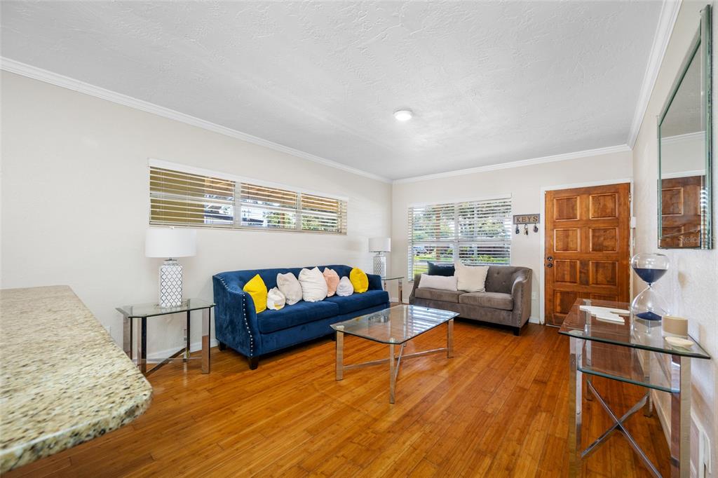 A living room features hardwood floors, a blue sofa, a grey loveseat, and glass tables — 6410 WALTON WAY, TAMPA, FL
