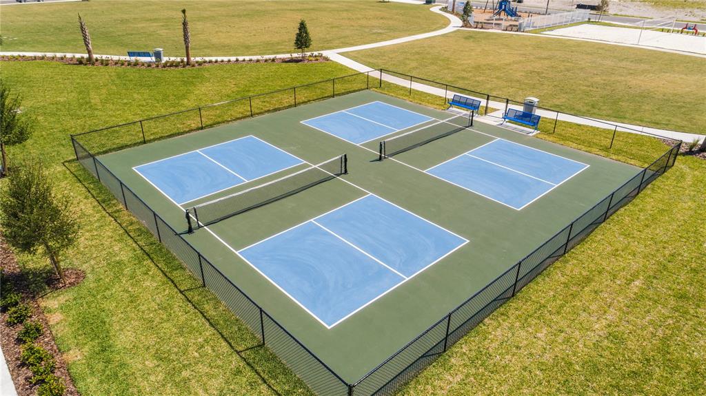 An aerial view of four fenced pickleball courts situated in a grassy park area — 5566 RONIN DRIVE, ST CLOUD, FL