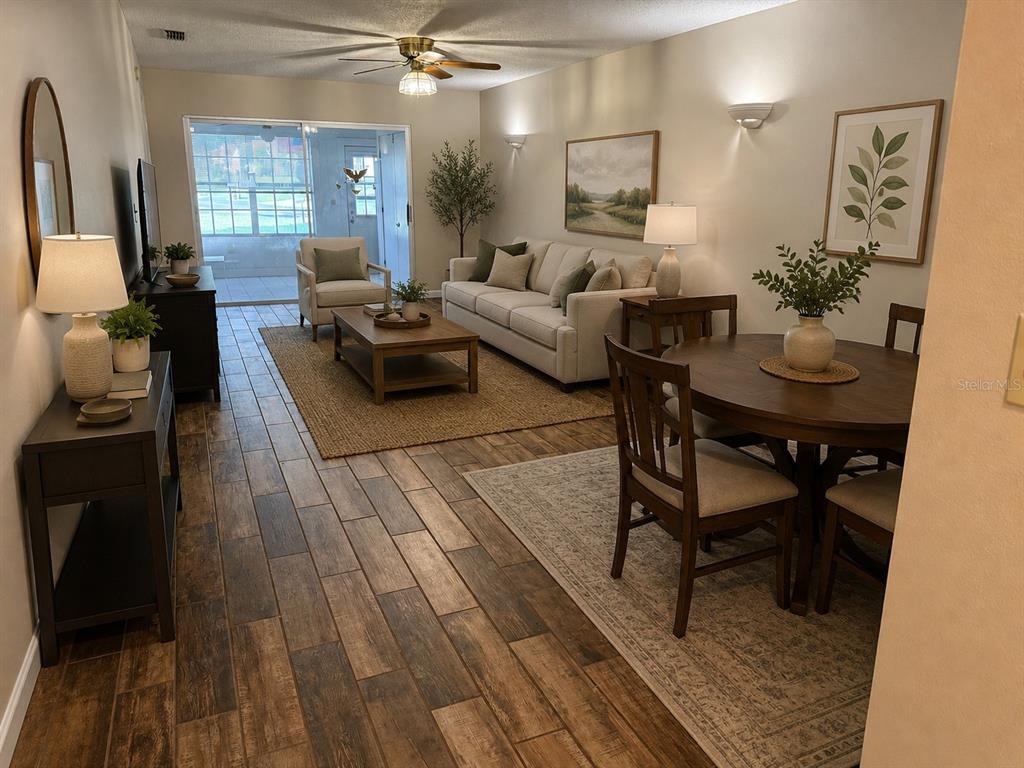 A living and dining area features wood-look tile flooring, a beige sofa, and a round table — 11403 VERSAILLES LANE UNIT E, PORT RICHEY, FL