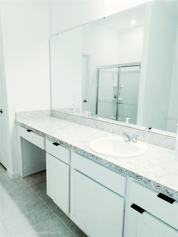 A bathroom vanity with white cabinets, a speckled countertop, and a large wall mirror — 409 CONWAY AVENUE, ST CLOUD, FL