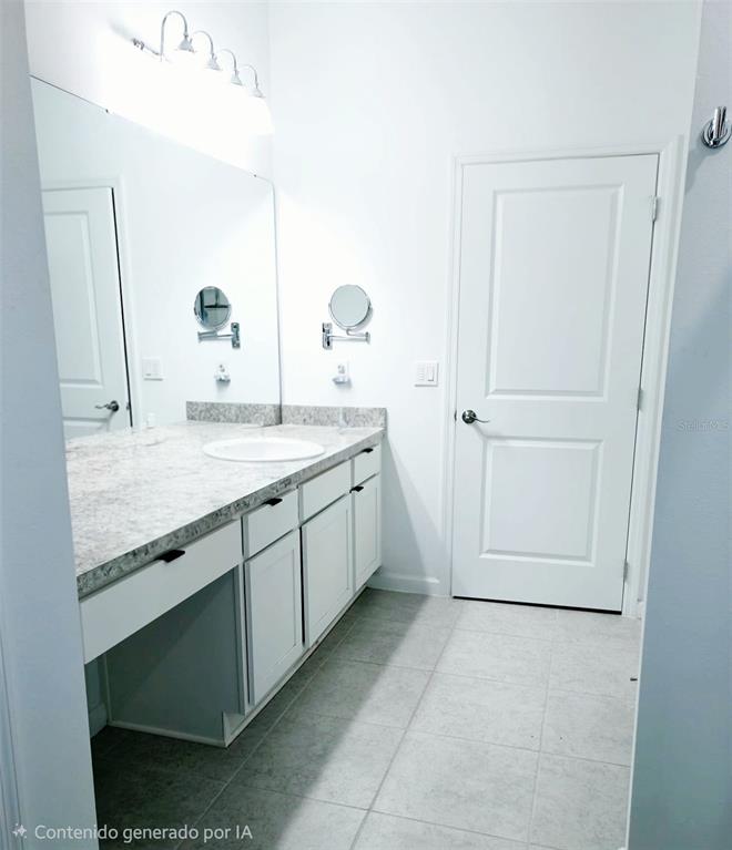 A bathroom features a white vanity with a stone countertop, a mirror, and tiled flooring — 409 CONWAY AVENUE, ST CLOUD, FL
