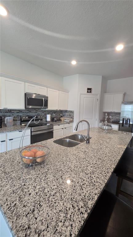 A kitchen features white cabinetry, granite countertops, a large island with a sink, and stainless appliances — 409 CONWAY AVENUE, ST CLOUD, FL