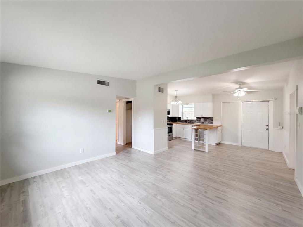 An open-concept living area features light wood-look flooring and a kitchen with white cabinetry — 1371 JEFFORDS STREET, CLEARWATER, FL