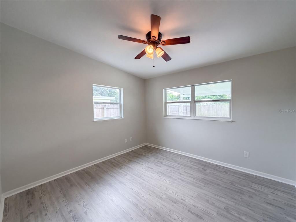An empty bedroom features light gray walls, wood-look flooring, a ceiling fan, and two windows — 1371 JEFFORDS STREET, CLEARWATER, FL