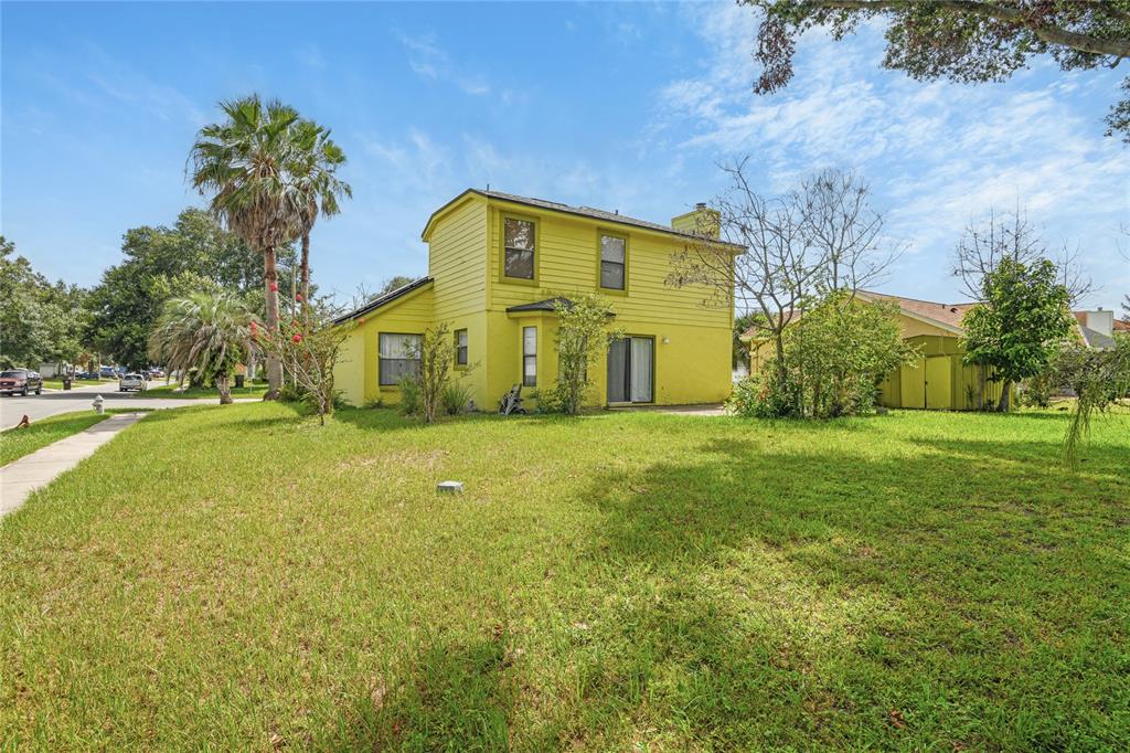 A two-story yellow house with a large lawn, palm trees, and a detached shed — 1469 MONA DRIVE, KISSIMMEE, FL