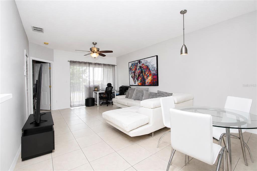 A living room features a white sectional sofa, colorful horse artwork, and light tile flooring — 508 VILLA DEL SOL CIRCLE UNIT 204, ORLANDO, FL