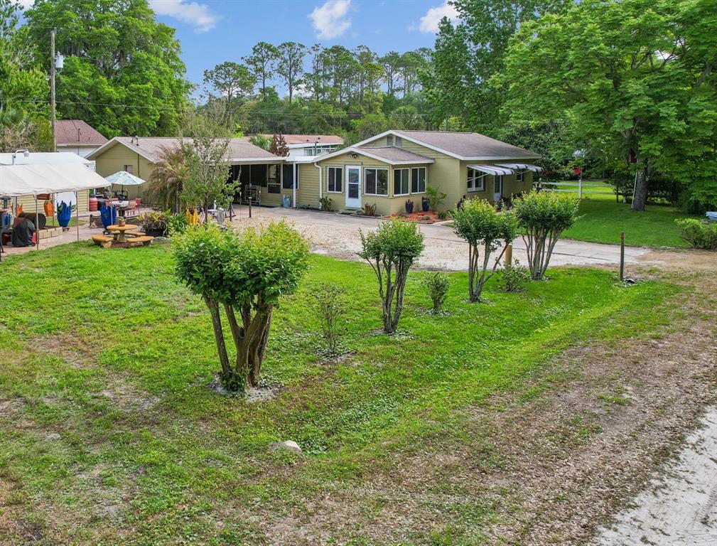 A green one-story house with a gravel driveway and a lawn featuring several small trees — 110 SHAFFER AVENUE, CRESCENT CITY, FL