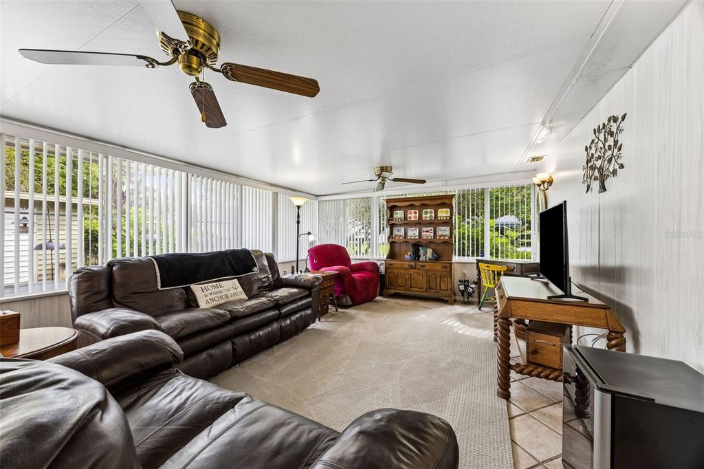 A living room features a brown leather sofa, a red armchair, and a wooden hutch — 110 SHAFFER AVENUE, CRESCENT CITY, FL
