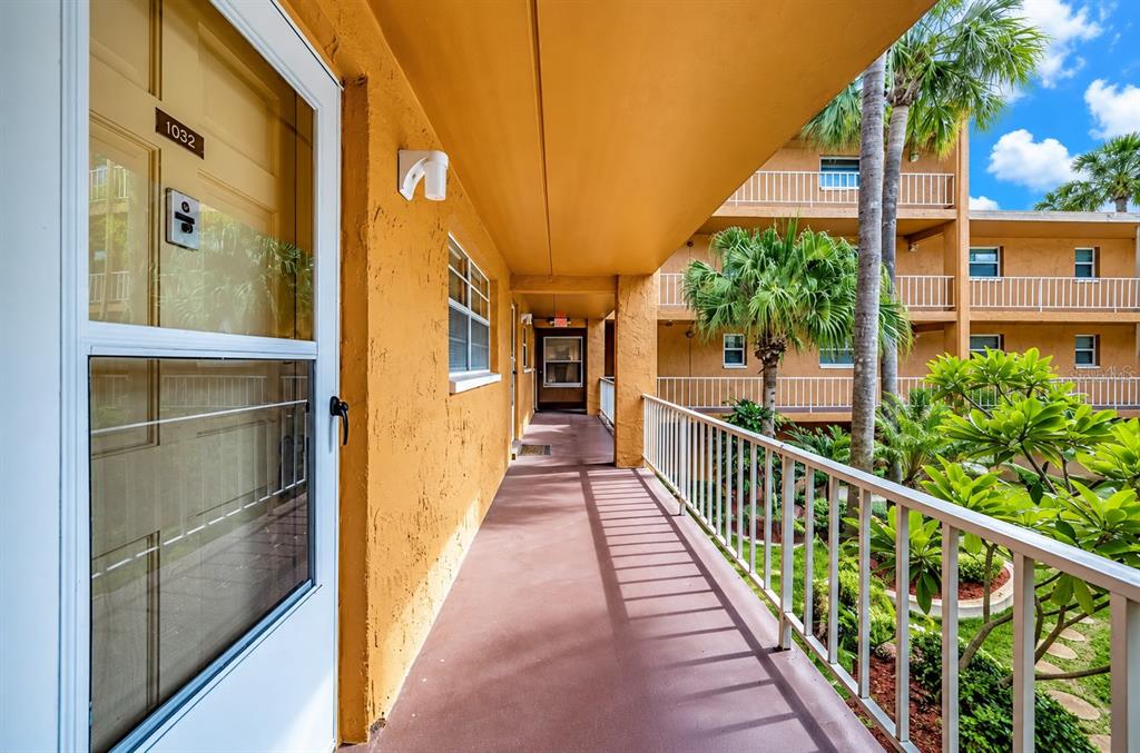 An outdoor swimming pool is surrounded by multi-story apartment buildings and several tall palm trees — 12760 INDIAN ROCKS ROAD UNIT 1030 (Furnished), LARGO, FL