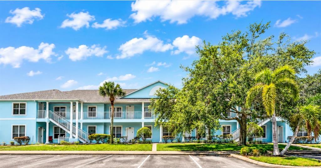 A two-story light blue apartment building sits behind a parking lot with several cars — 3111 SUN LAKE COURT UNIT B, KISSIMMEE, FL