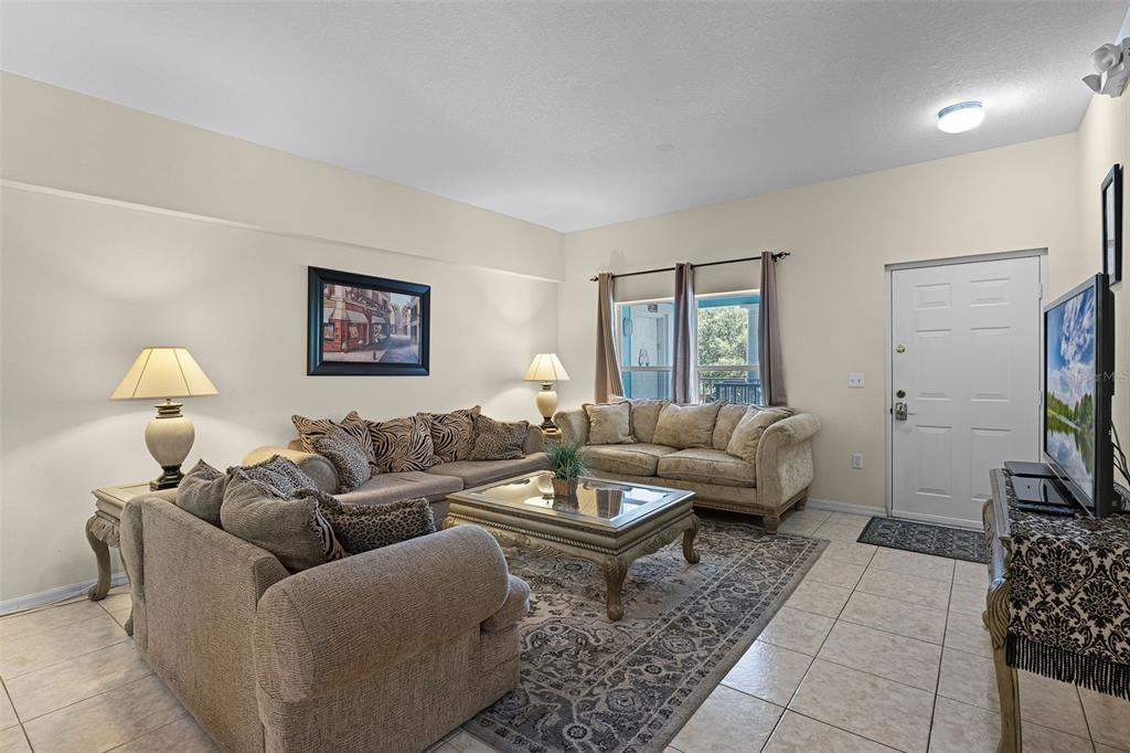 A dining room features a light wood table with six chairs, tiled floors, and two clocks — 3111 SUN LAKE COURT UNIT B, KISSIMMEE, FL