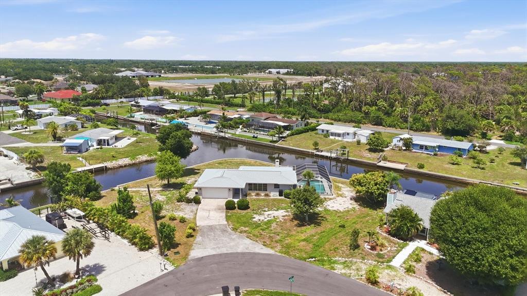 An aerial view shows a waterfront house with a pool cage along a canal — 898 E 6TH STREET, ENGLEWOOD, FL