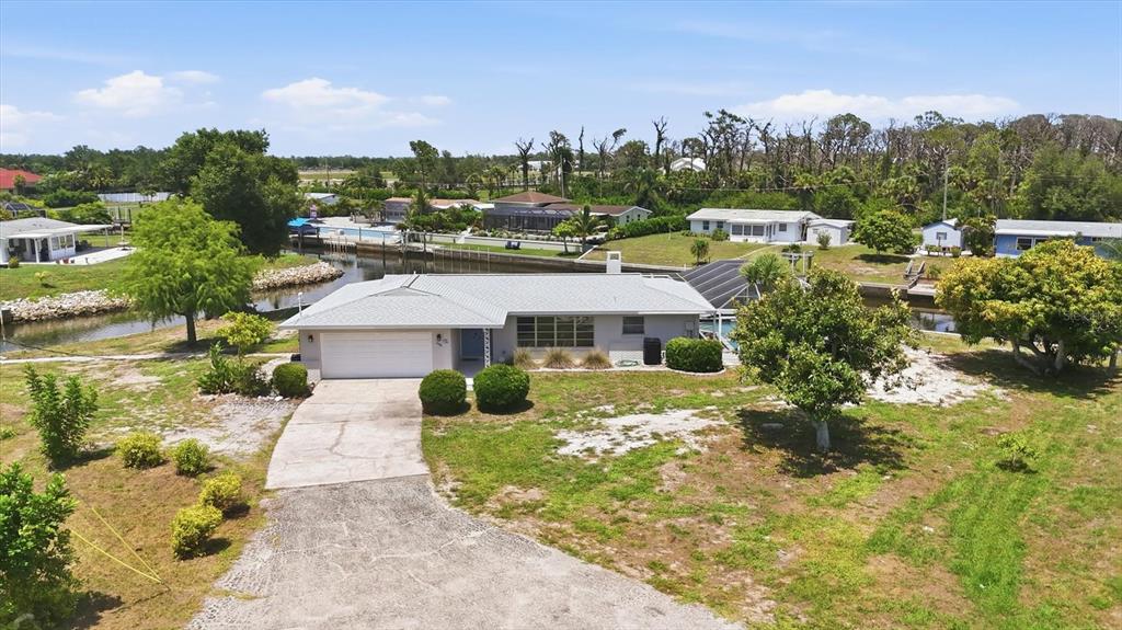An aerial view shows a single-story house with a pool cage and a canal — 898 E 6TH STREET, ENGLEWOOD, FL