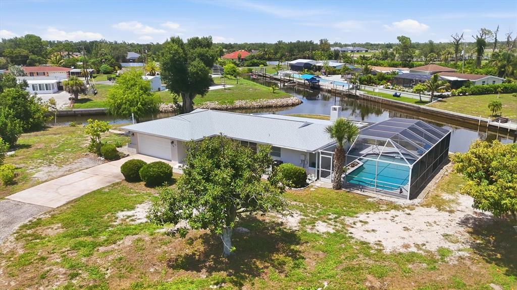A single-story house with a white garage, a light-colored roof, and a screened-in pool area — 898 E 6TH STREET, ENGLEWOOD, FL