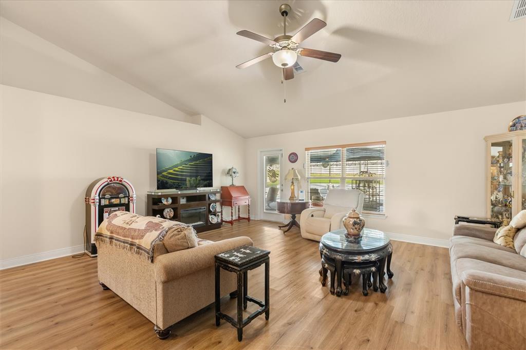 A living room features light wood-look flooring, a vaulted ceiling, and a jukebox — 906 EDITH DRIVE, FRUITLAND PARK, FL