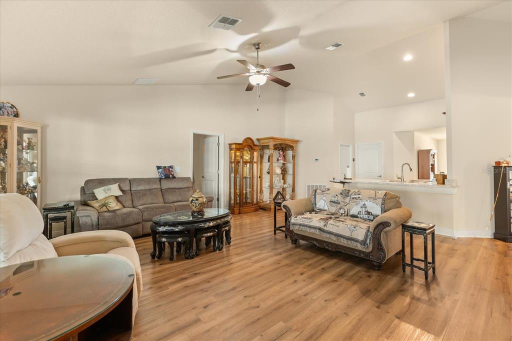 A dining room features light wood flooring, a chandelier, and two large wooden cabinets — 906 EDITH DRIVE, FRUITLAND PARK, FL
