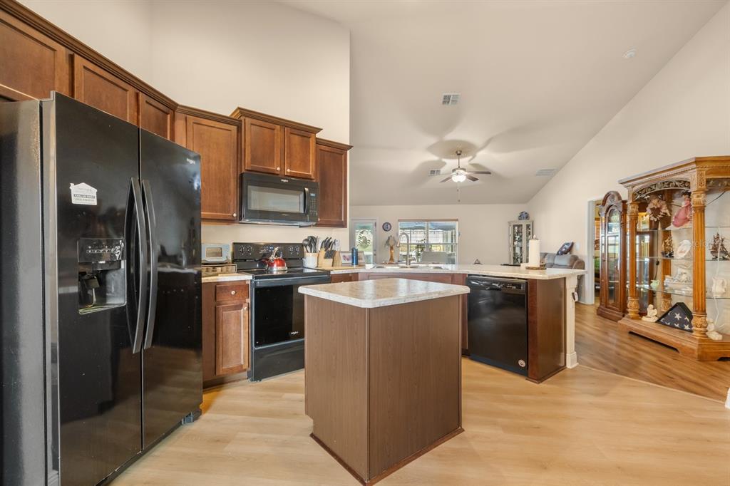 A kitchen features dark wood cabinets, black appliances, a central island, and light-colored countertops — 906 EDITH DRIVE, FRUITLAND PARK, FL