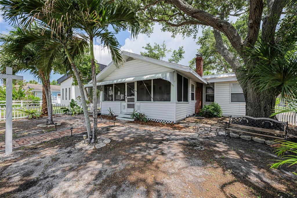 A white house with a front porch and palm trees sits behind a white picket fence — 3829 2ND AVENUE N, ST PETERSBURG, FL